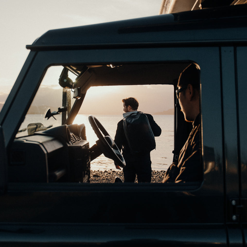 A man standing by a car with a black Stubble & Co Kit Bag 30L on his back