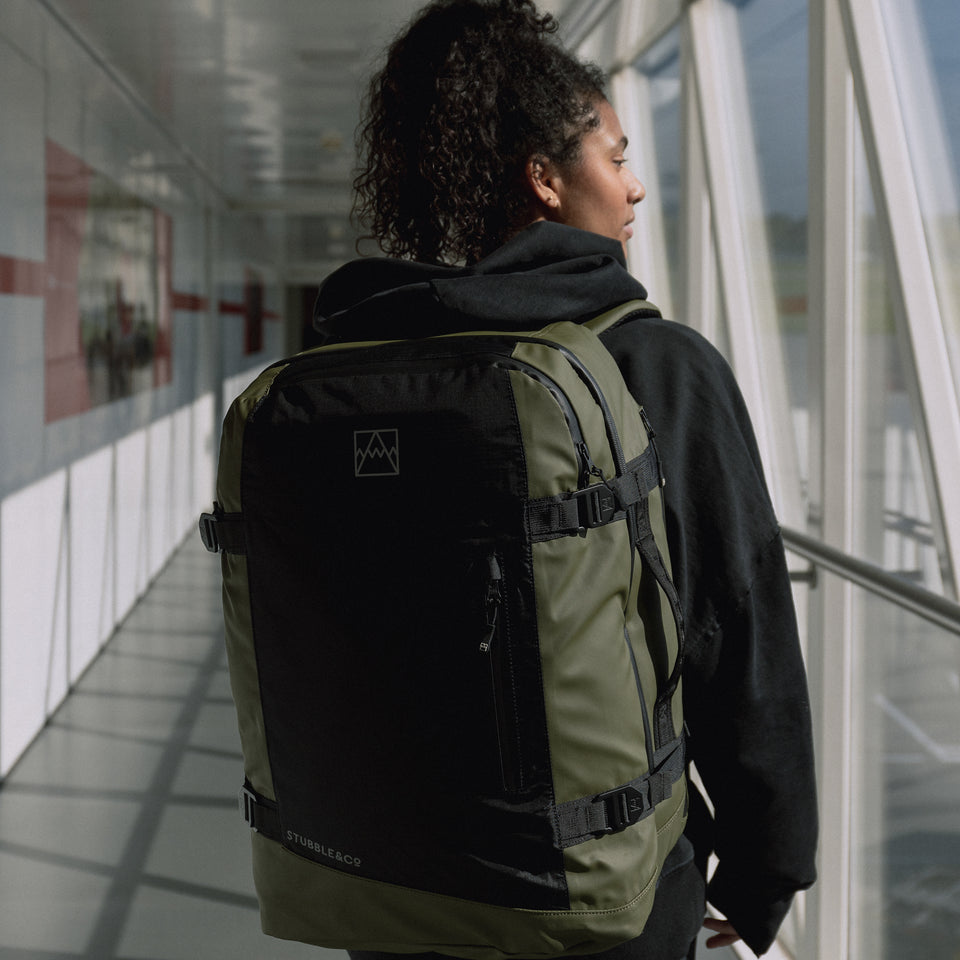 Women wearing a large black and green backpack walking in an airport terminal