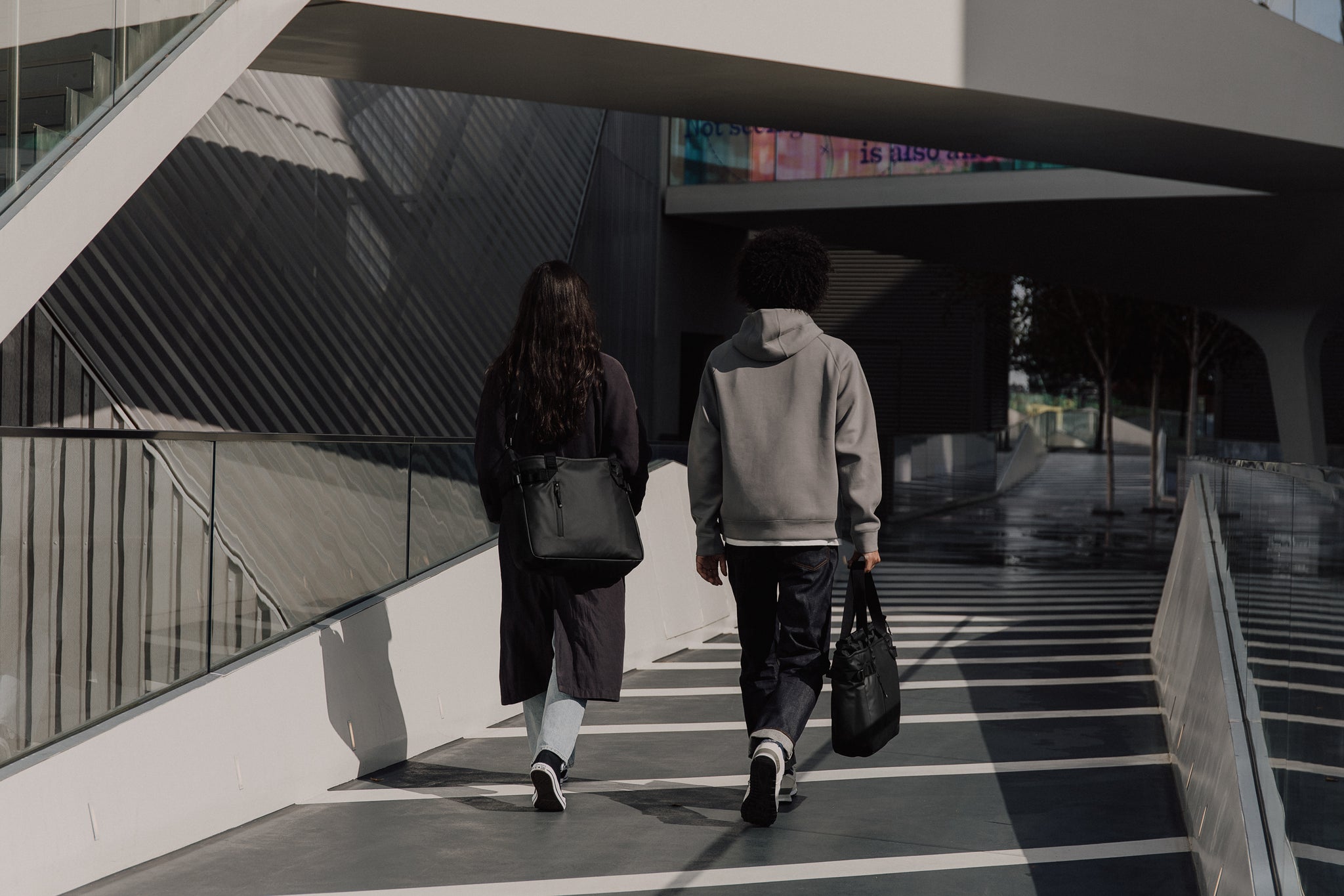 Man and women walking with black tote bag