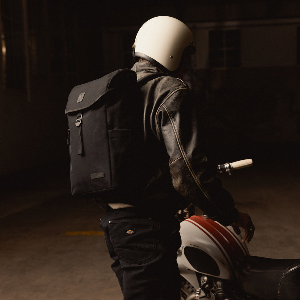 A man getting onto a motorbike with a Backpack 20L on his back in All Black