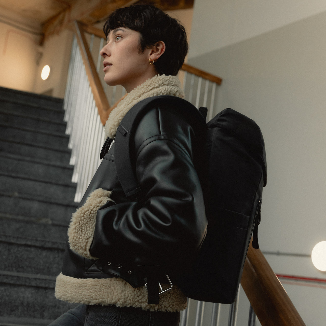 A woman standing on the stairs wearing a backpack 20L on her back in All Black