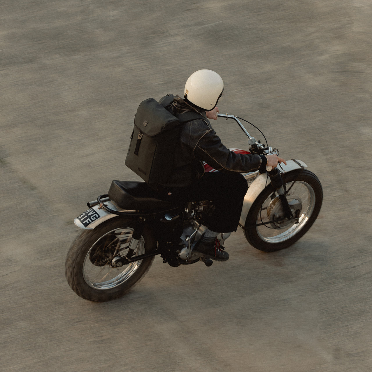 A man riding a motorbike with a Backpack 20L on his back in Pirate