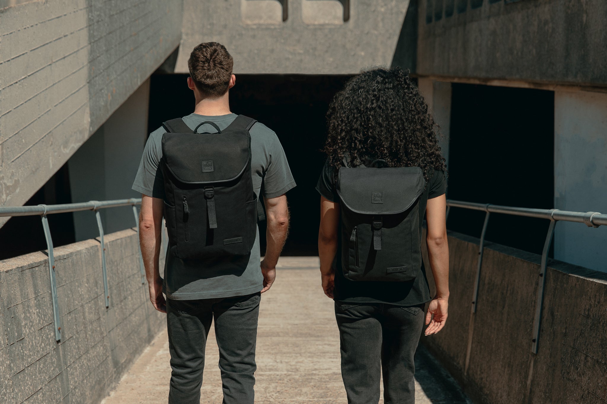  A man and woman walking away from the camera with a canvas Backpack on their backs