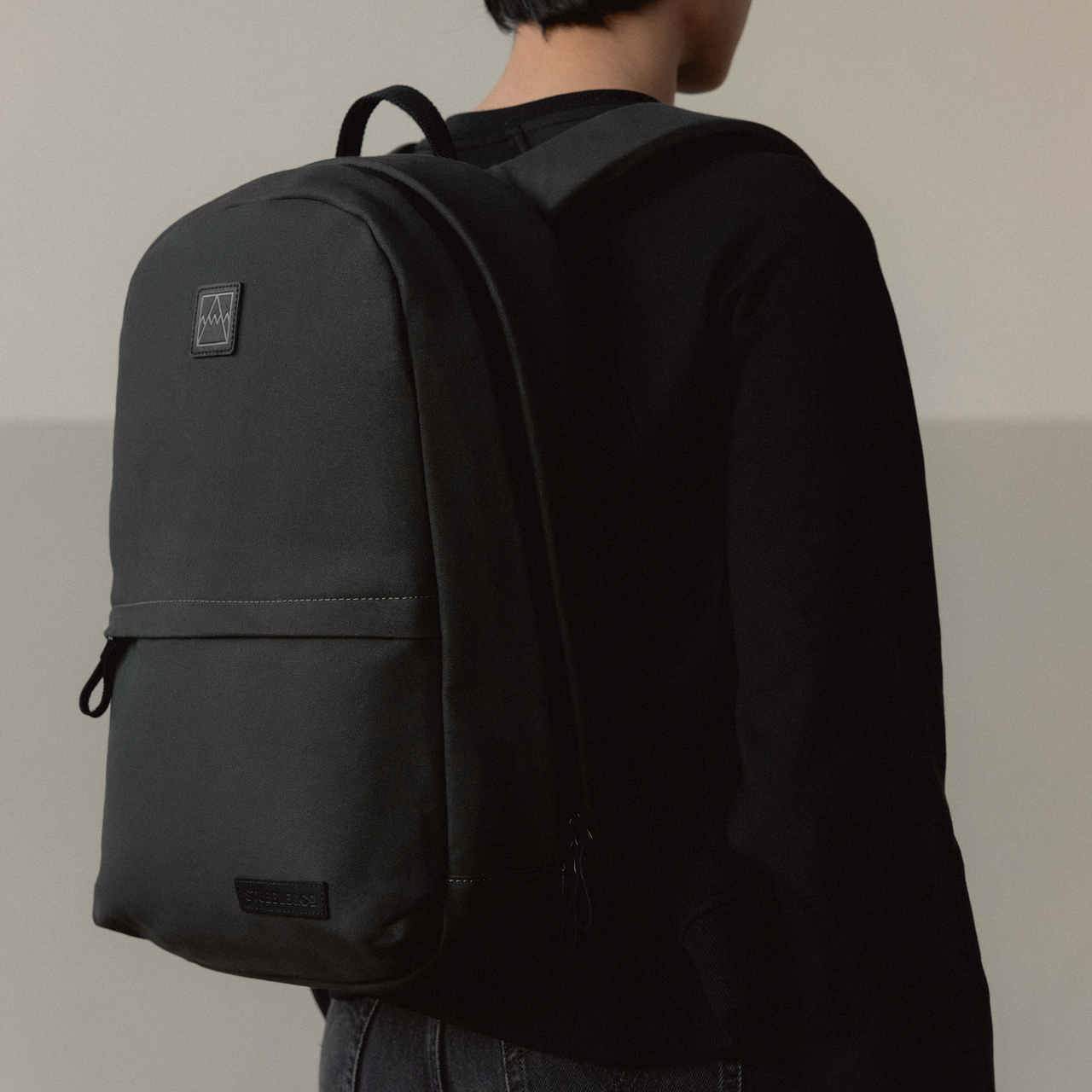 A close up of a Classic Backpack 15L on her back in All Black