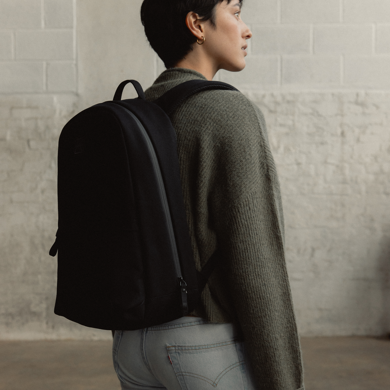 A woman wearing a Classic Backpack 15L in All Black on her back