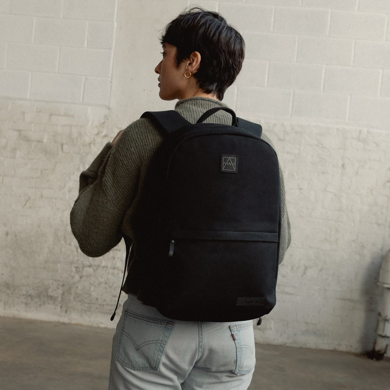 A woman facing away wearing a Classic Backpack 15L on her back in All Black