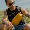 a man sitting on the grass with a Yellow crossbody on his front