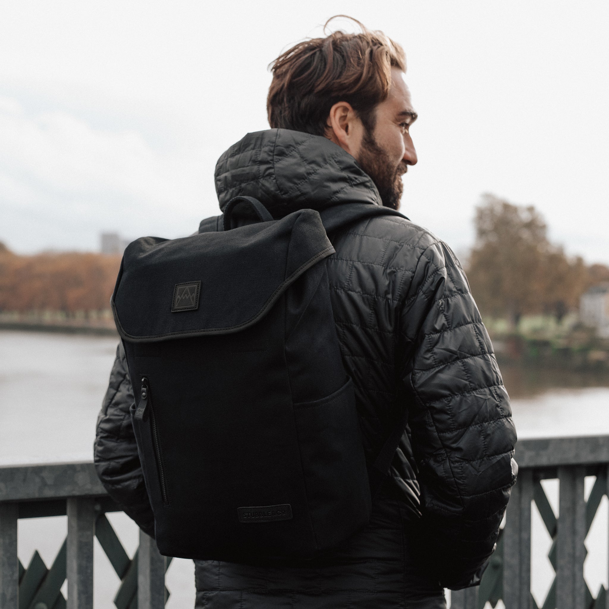 A man standing on the bridge with an All Black Daypack Outlet in his back