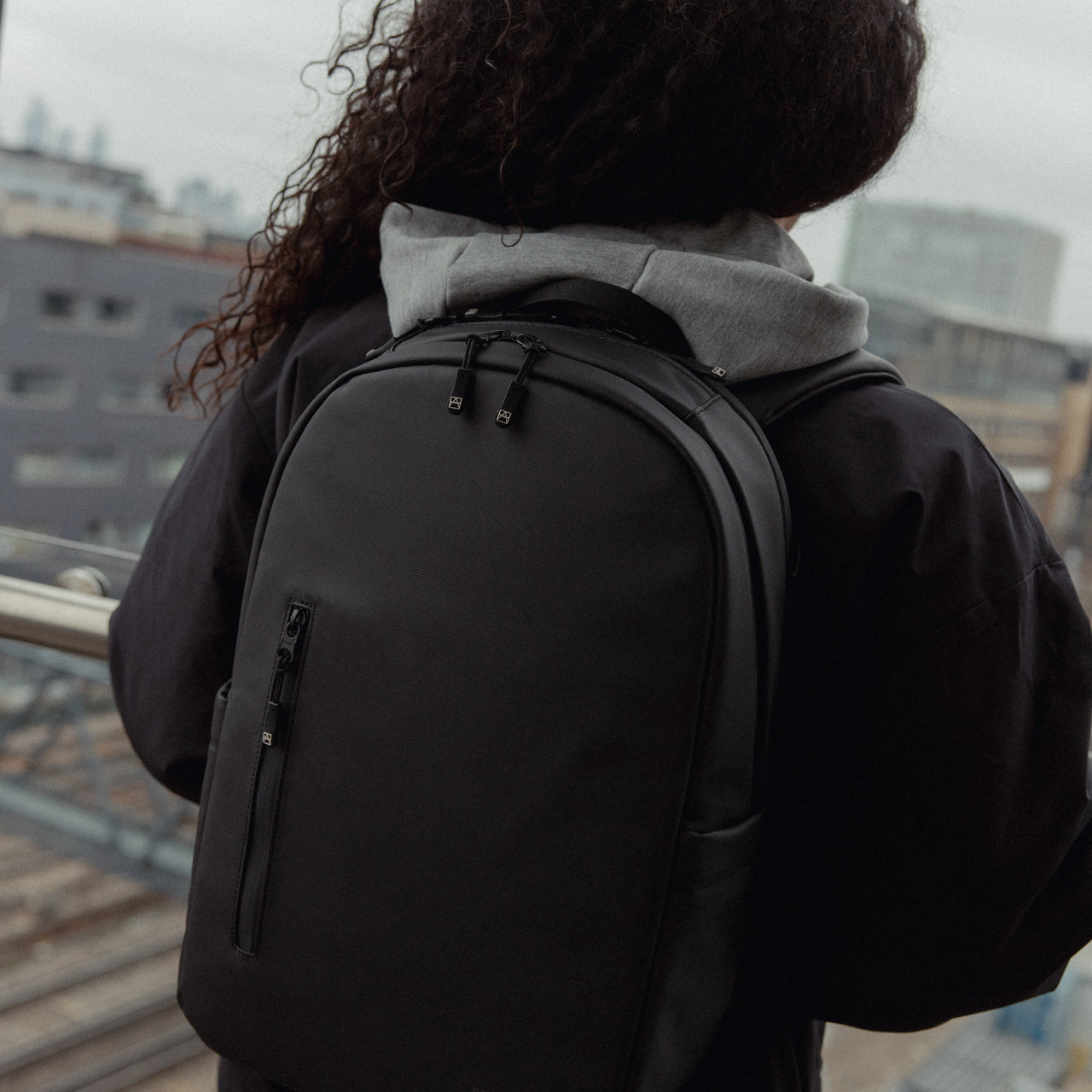 A close up of an Everyday Backpack 15L in All Black on a woman's back