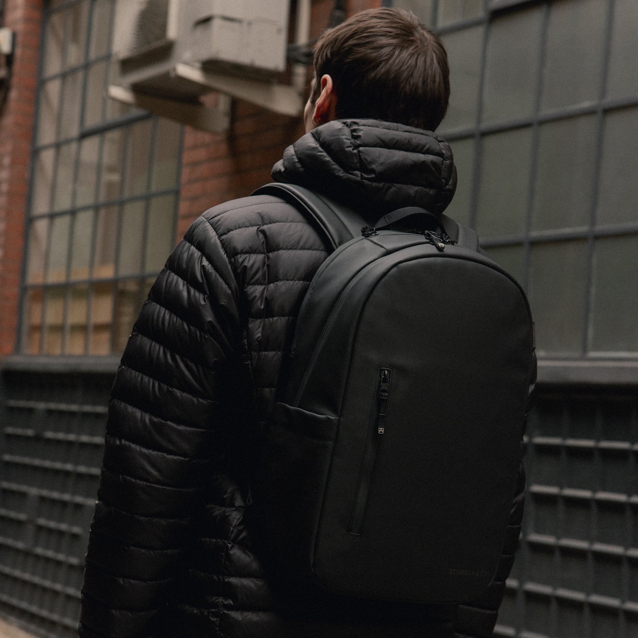 A man walking away with an Everyday Backpack 15L on his back in All Black