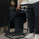 A lifestyle shot of the  Hybrid Backpack 30L in All Black as a  man places it into the bag size measurer at the airport