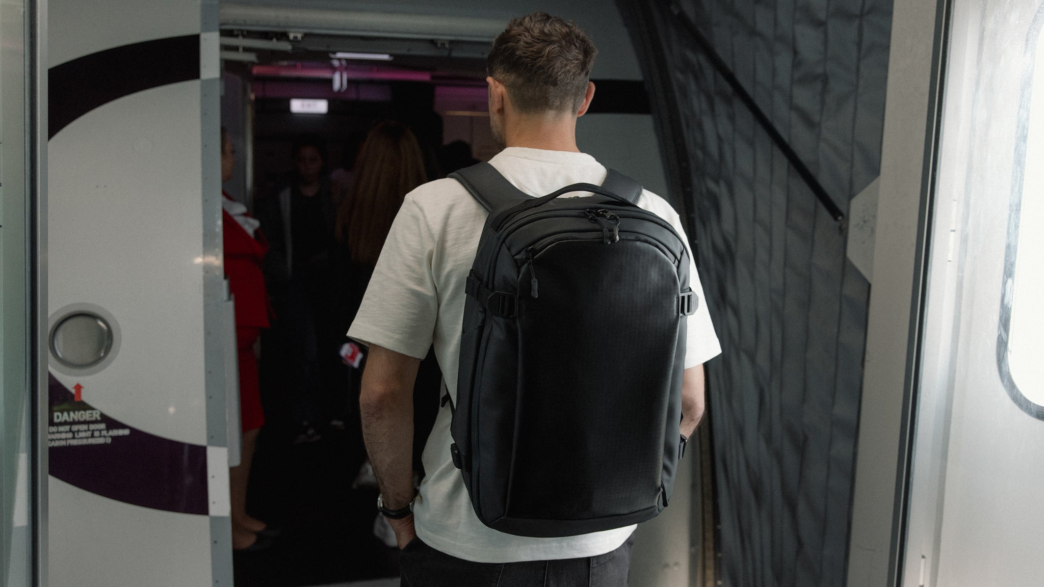 A man boarding a plane wearing a hybrid backpack 30l on his back