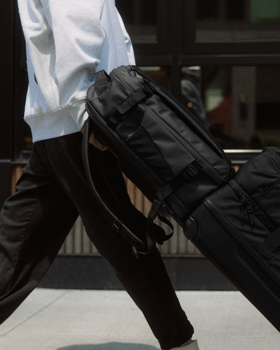 a close up shot of a man man wheeling a Hybrid backpack 30L using its luggage sleeve