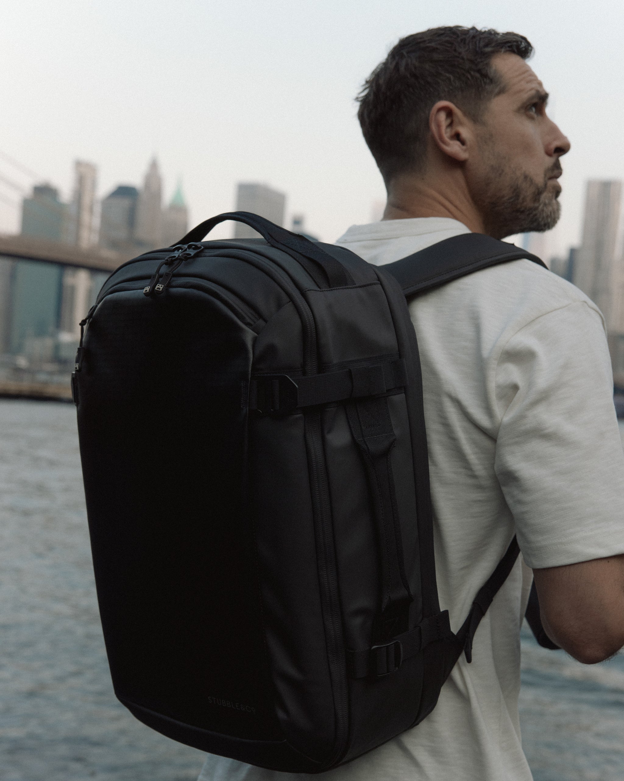 A man wearing a Hybrid Backpack 30L on his back with New York city in the backgorund