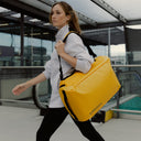 A woman walking with her a Kit Bag 30L in Yellow on her shoulder