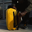 A man placing a laptop into the compartment of  a Kit Bag 30L in Yellow