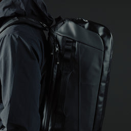 A close up studio shot of a man wearing a kit bag 40l on his back in All Black