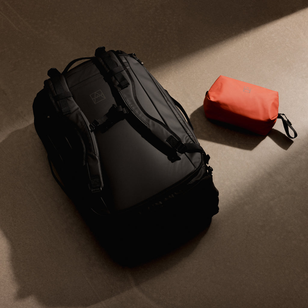 a studio shot of a kit bag 65l and an orange wash bag on the floor as a creative flat lay