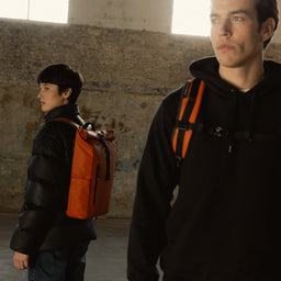 A man and woman wearing a Roll Top in Rust on their backs