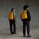 a man and woman standing facing away showing the back of a Yellow roll top 15l