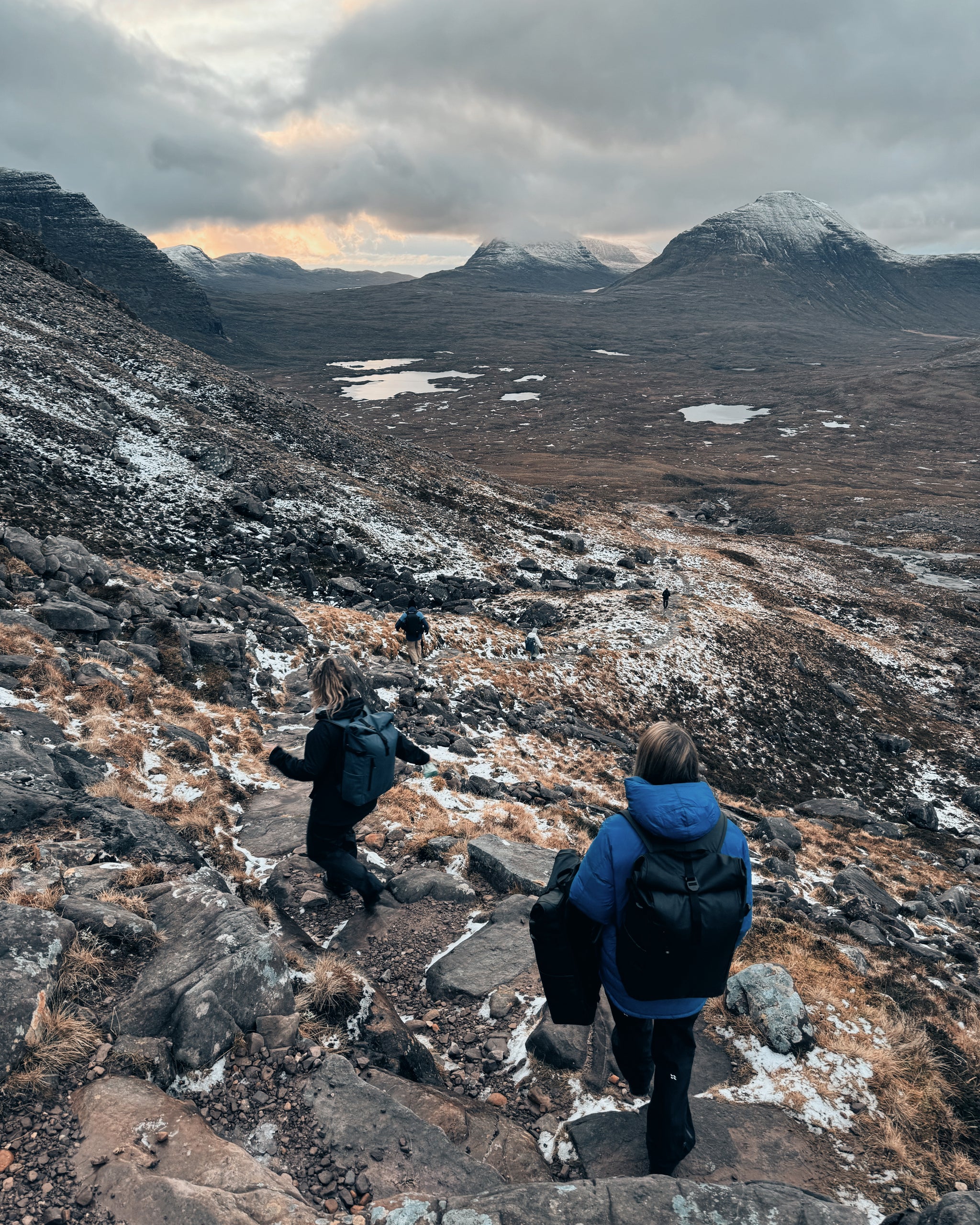 Two women on a hike down a mountain in Scotland with backpacks. 