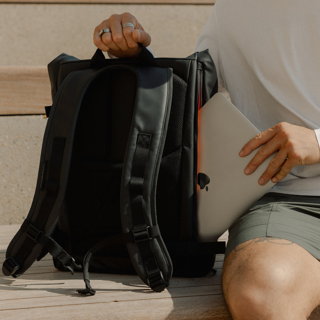 A close up of a man putting a laptop into an All Black Roll Top 20l