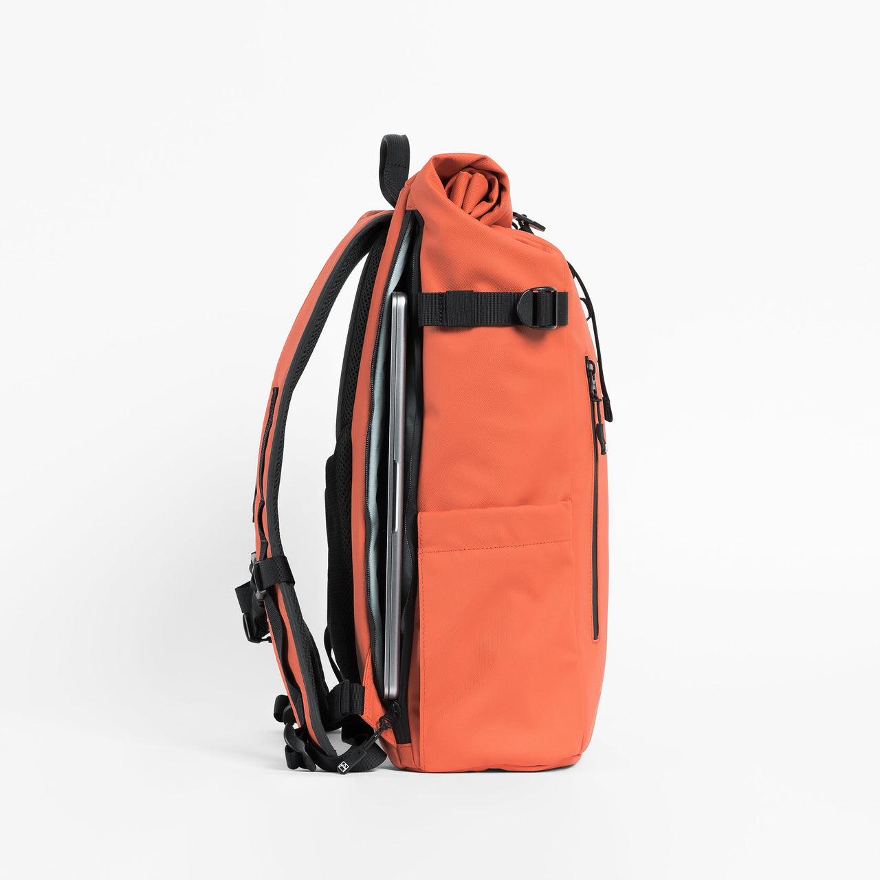 Side view of The Roll Top 20L backpack in Ember Orange with laptop compartment