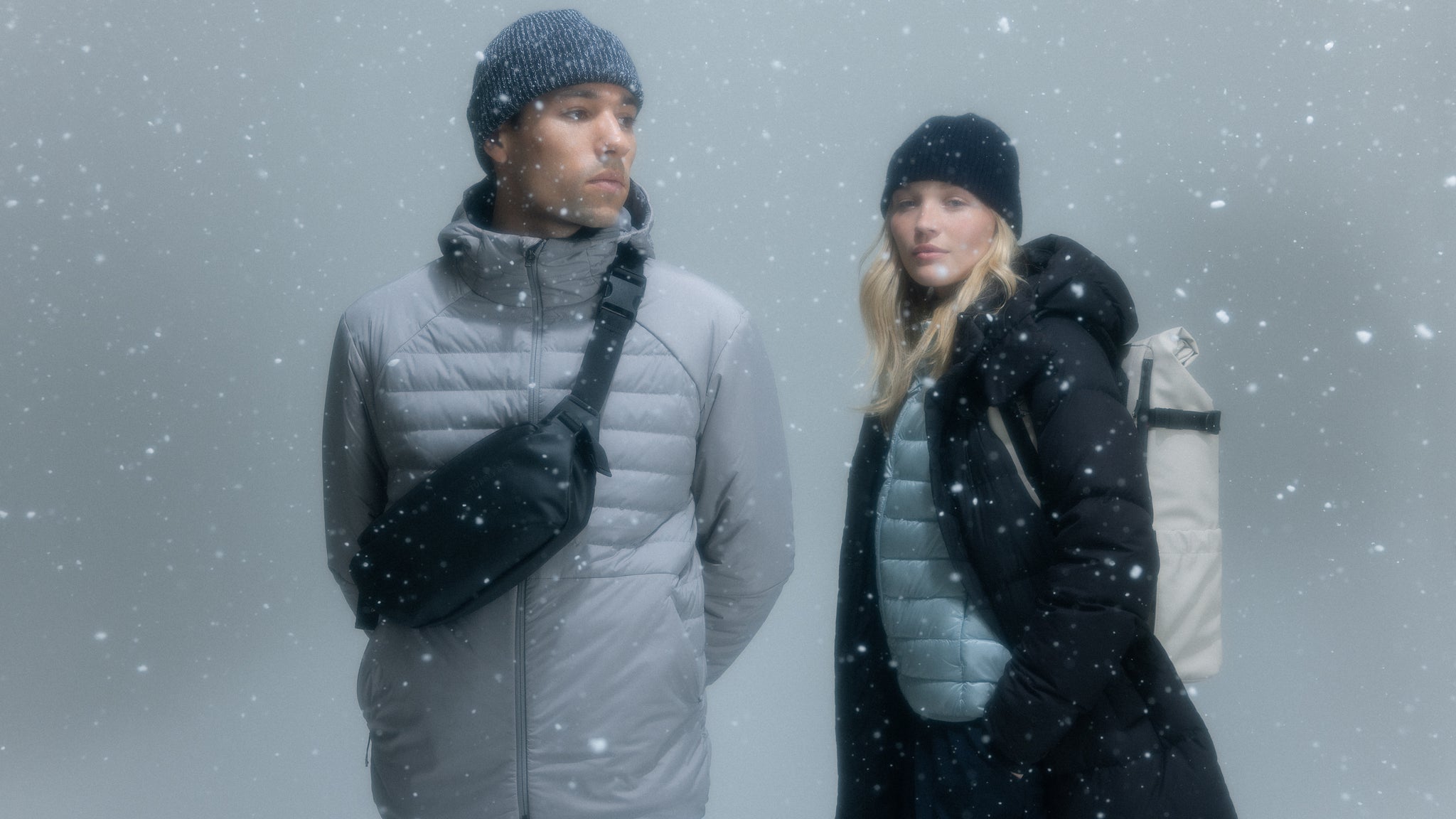 A man and woman wearing Stubble and Co bags in a studio with snow falling around