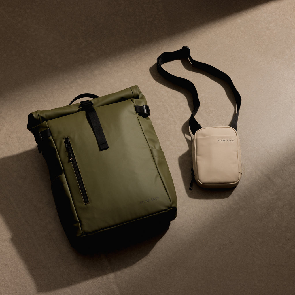 A studio shot of a green Roll top 20l and Sand Shoulder Bag on the floor as a creative flat lay