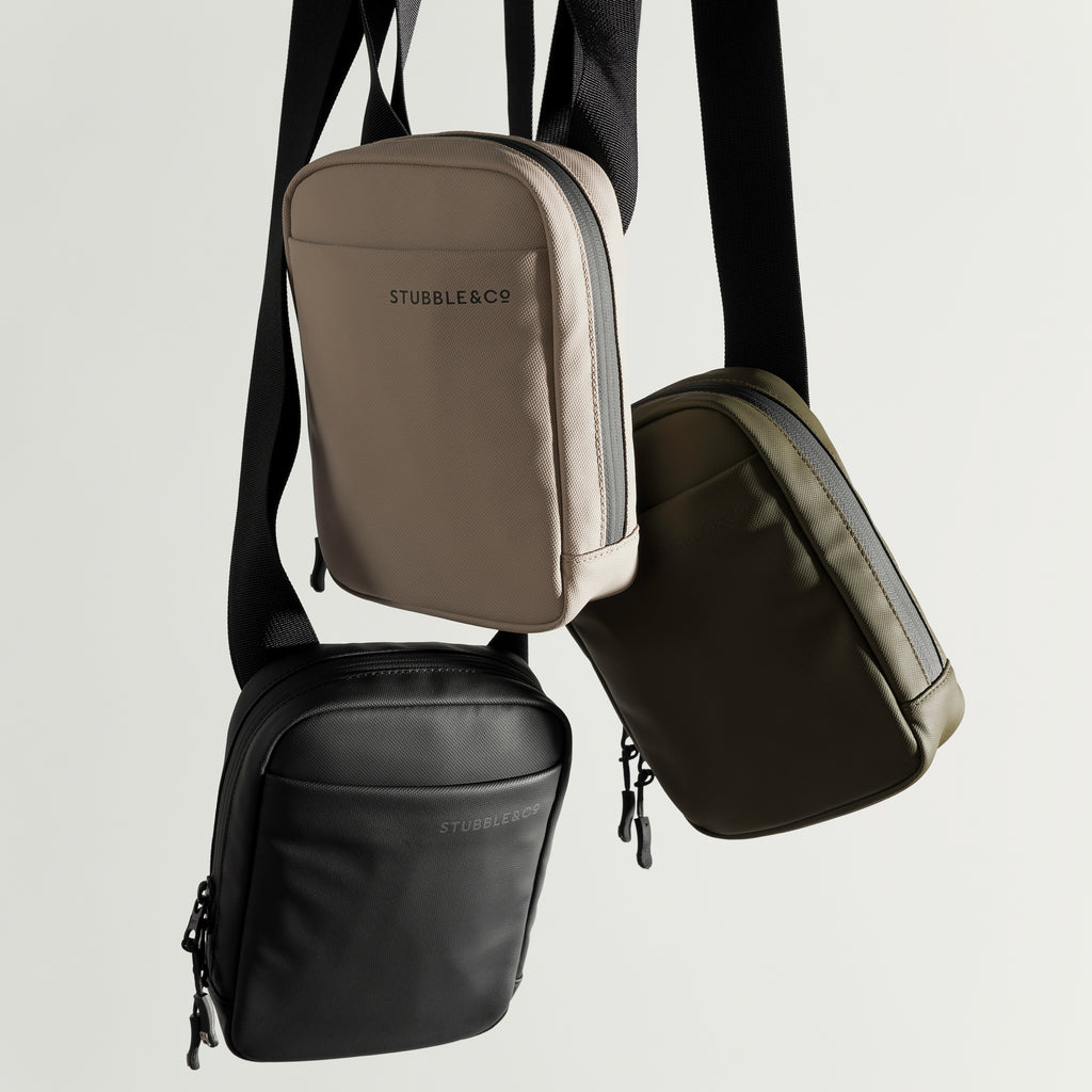 a studio shot of an all black, sand and urban gree shoulder bag hanging next to eachother