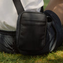 a close up of an All Black shoulder bag on the grass
