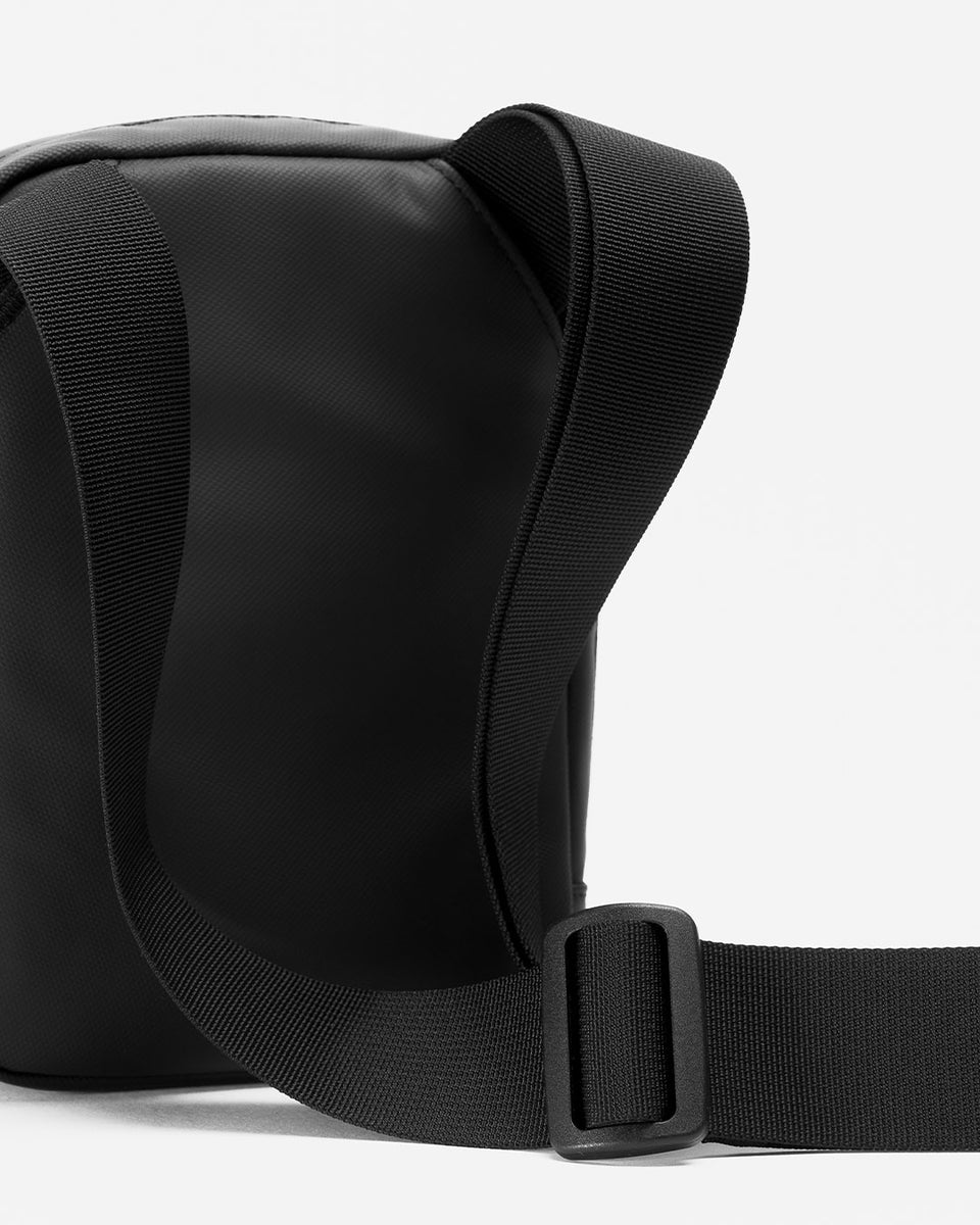 A studio shot of an all black shoulder bag showing the adjustable strap