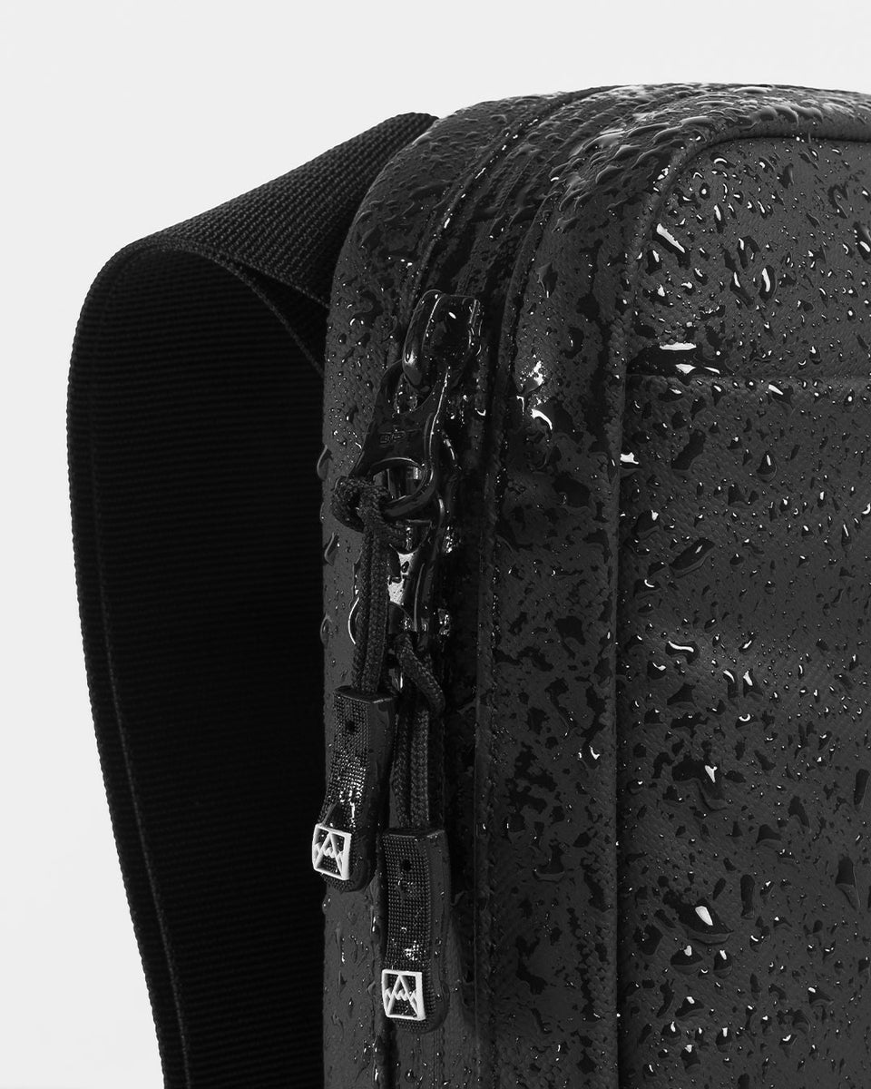 A studio shot of an all black shoulder bag showing the waterproof materials