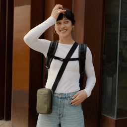 a woman wearing a black roll top and Urban Green shoulder bag