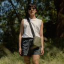 a woman standing in a field wearing an Urban Green shoulder bag