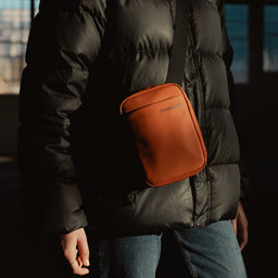 A close up shot of a woman wearing a Shoulder Bag in Rust