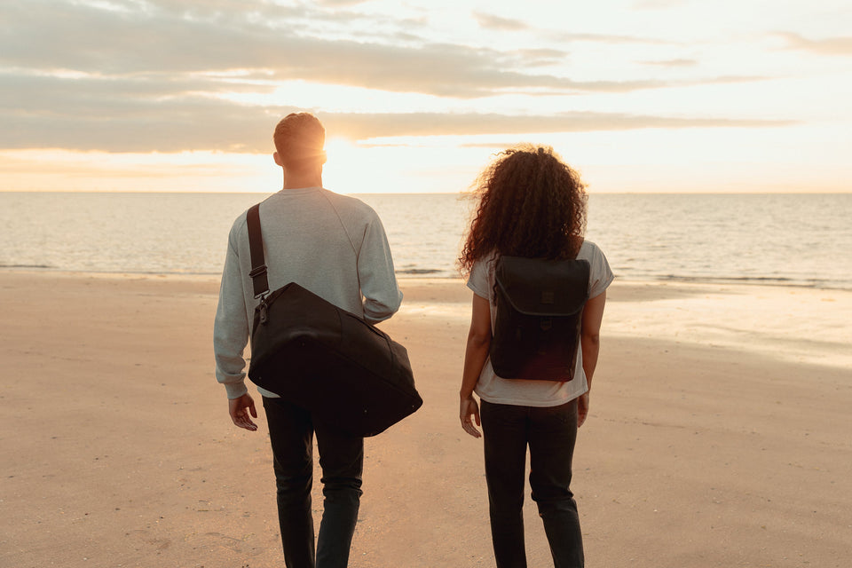 Man and women carry bags at sunset