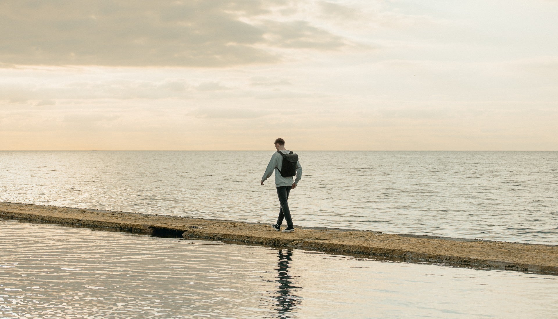 Man with backpack walking along the sea