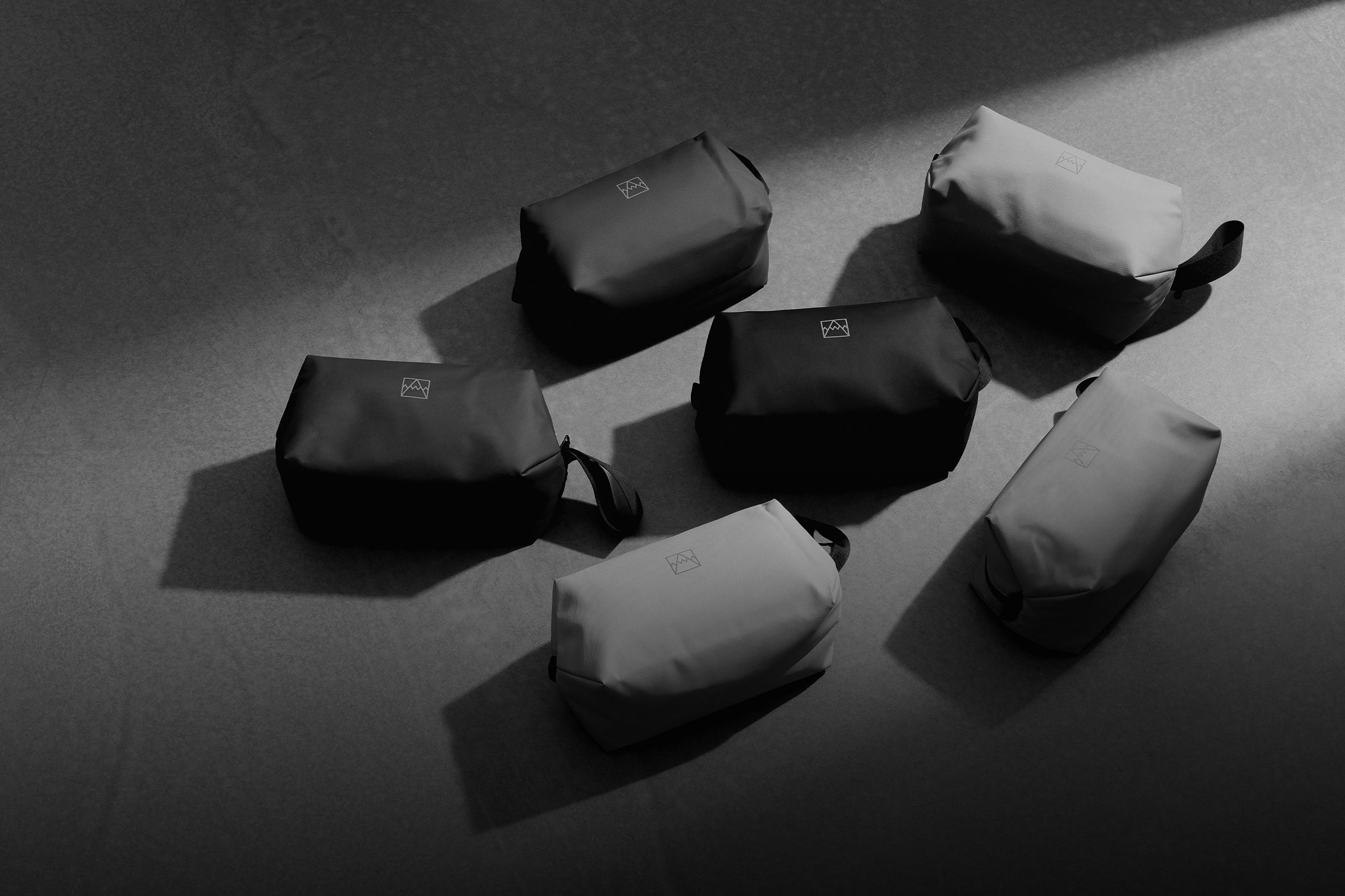 A black and white shot of 6 wash bags on the floor