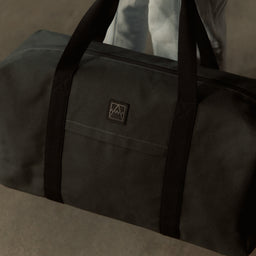 A close up shot of a woman holding a weekender 30l in Pirate down by her side