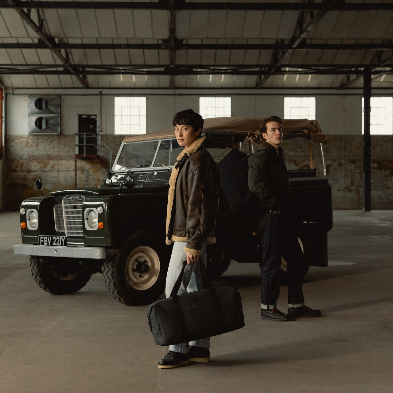 A man and woman standing in front of a car holding holding a weekender 30l in Pirate in her hand and he has it over his shoudler