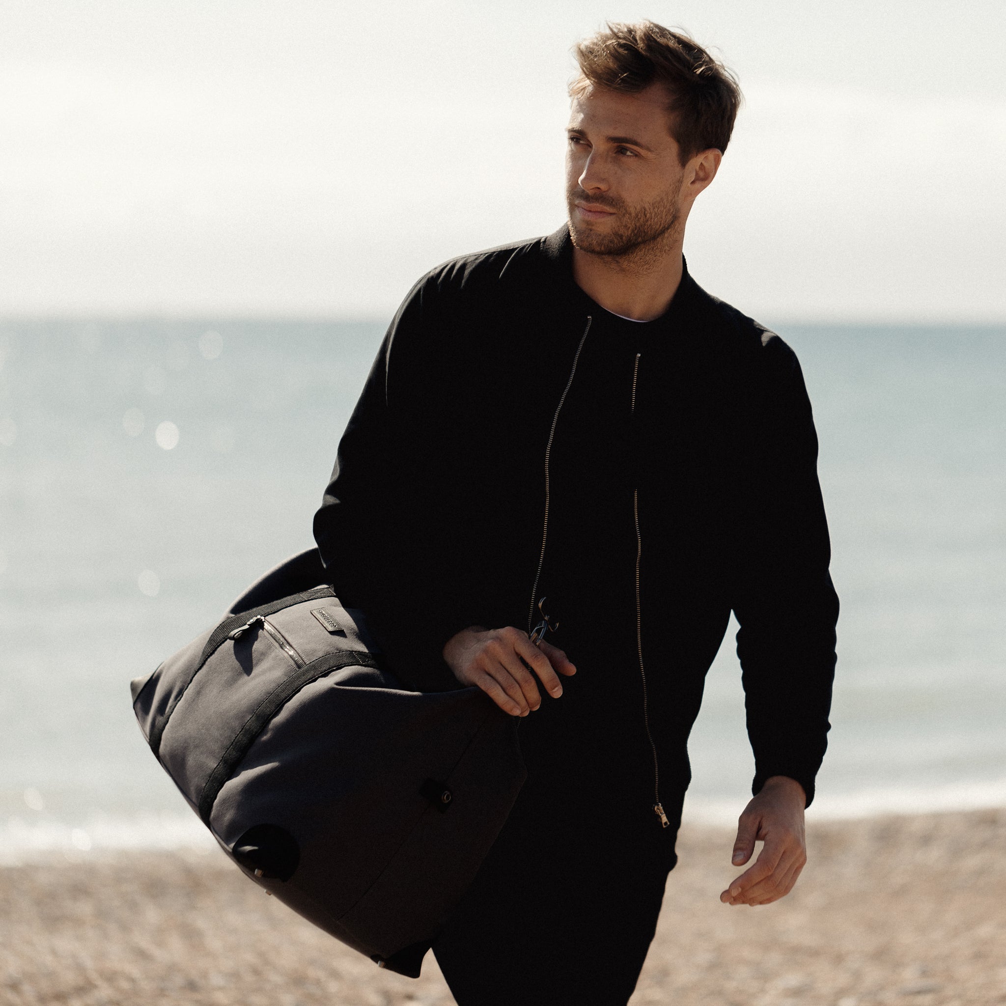 A man walking up with beach with Weekender Outlet in Grey