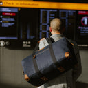 A man standing in a station with a Navy Weekender outlet on his shoulder